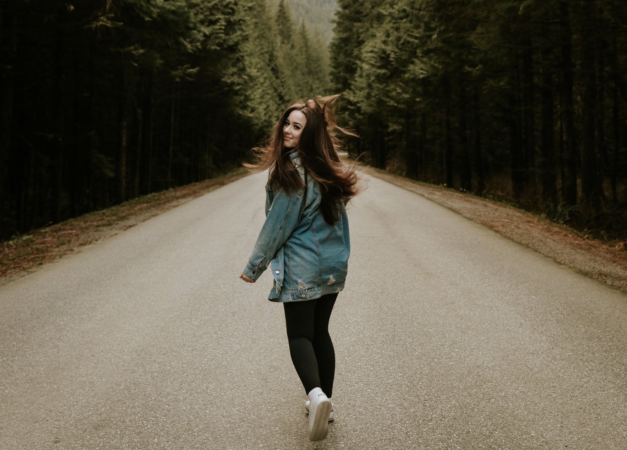 Woman walking a quiet forest road — McManus Photography