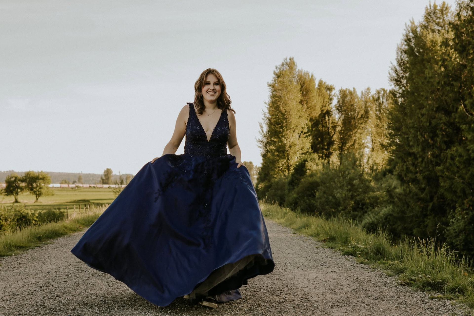 Young woman twirling a navy gown on a country road