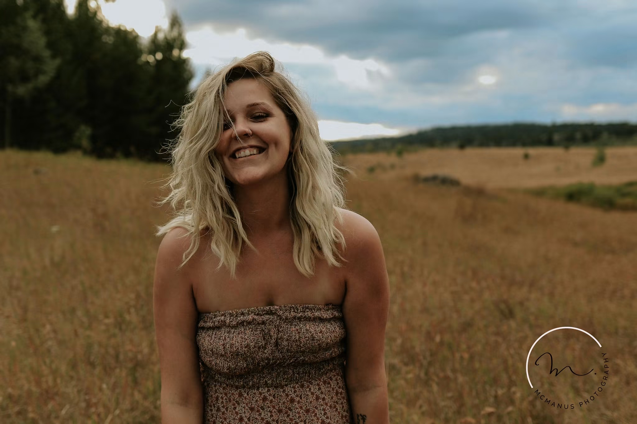 Laughing portrait of a woman in a summer field under storm clouds — McManus Photography