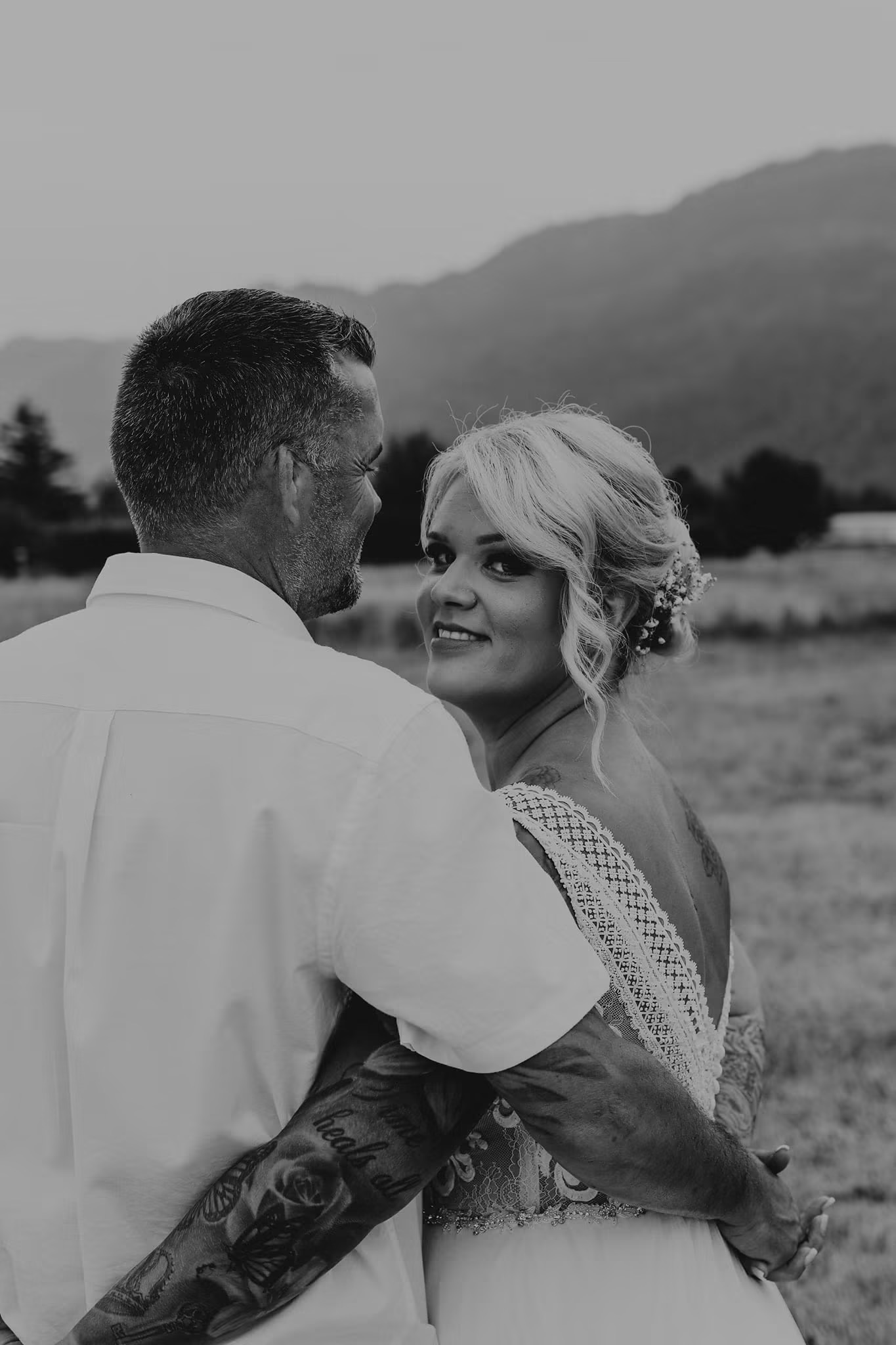 Black and white portrait of a bride looking back over her shoulder while dancing with her groom
