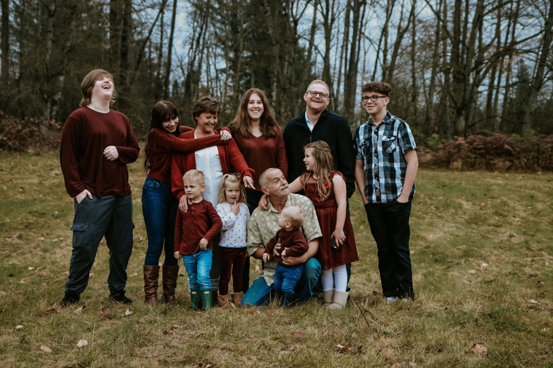 Large extended family laughing together in a winter field — McManus Photography