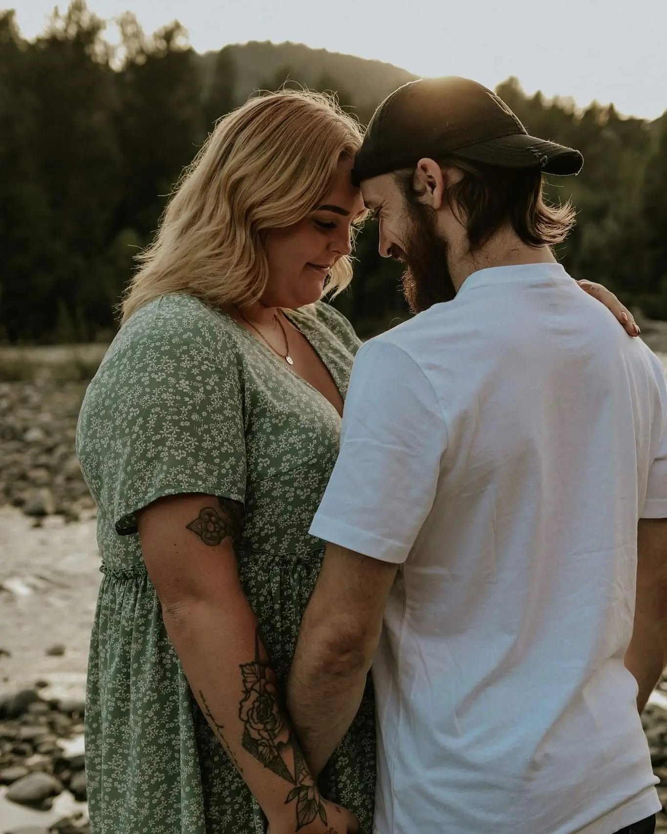 Couple forehead to forehead on a river rock bar at golden hour