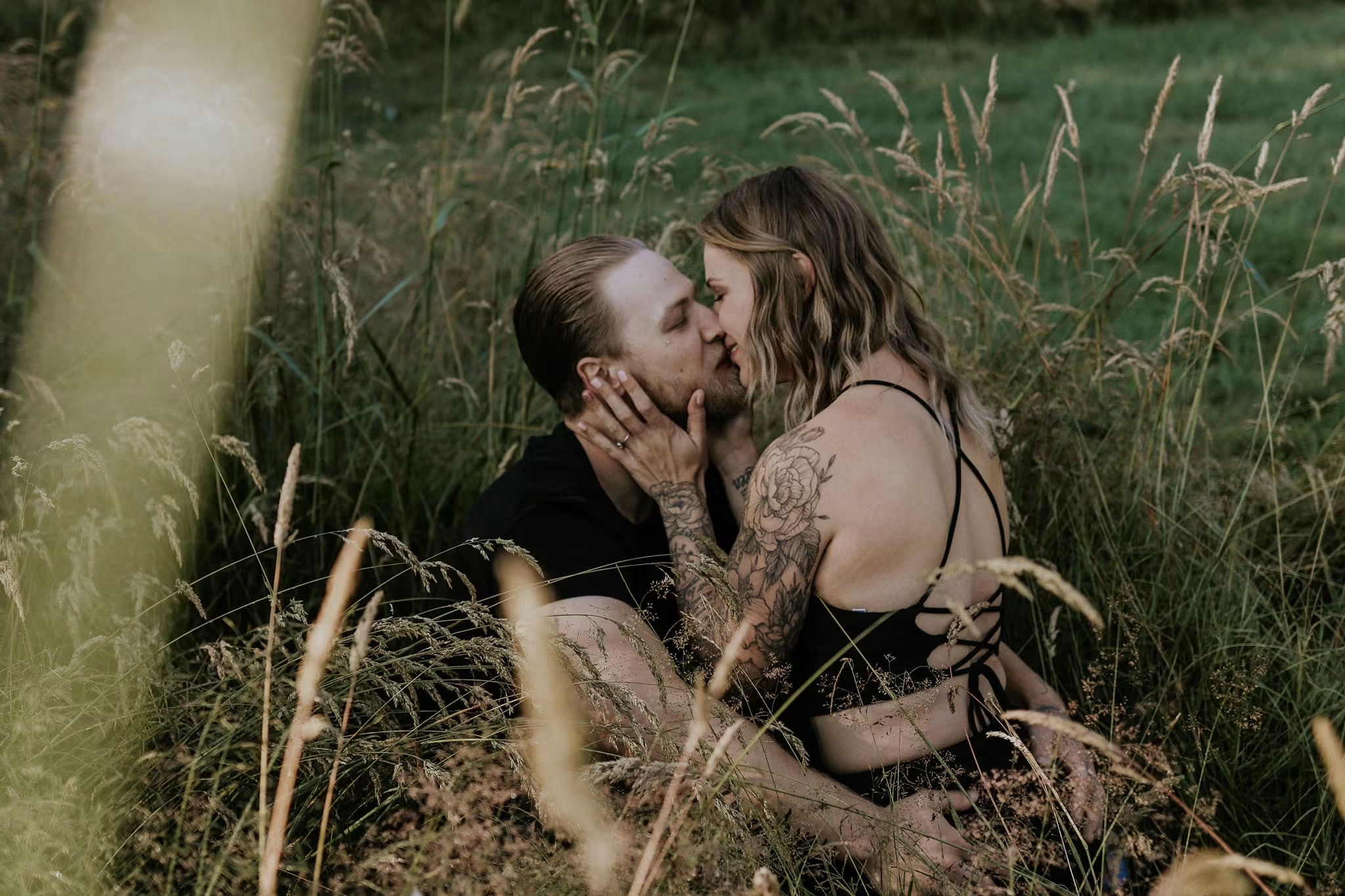 Couple kissing among tall summer grasses — McManus Photography