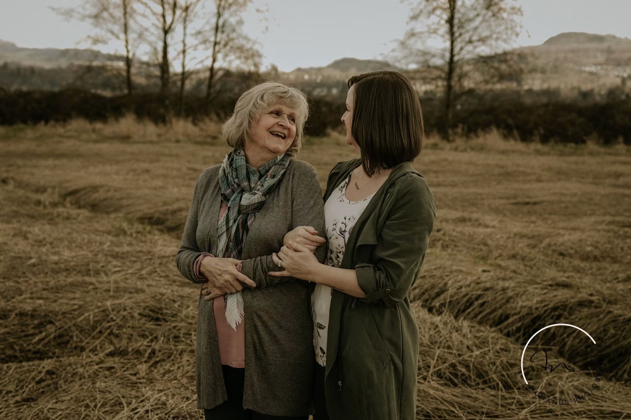 A mother and daughter laughing together in a golden field