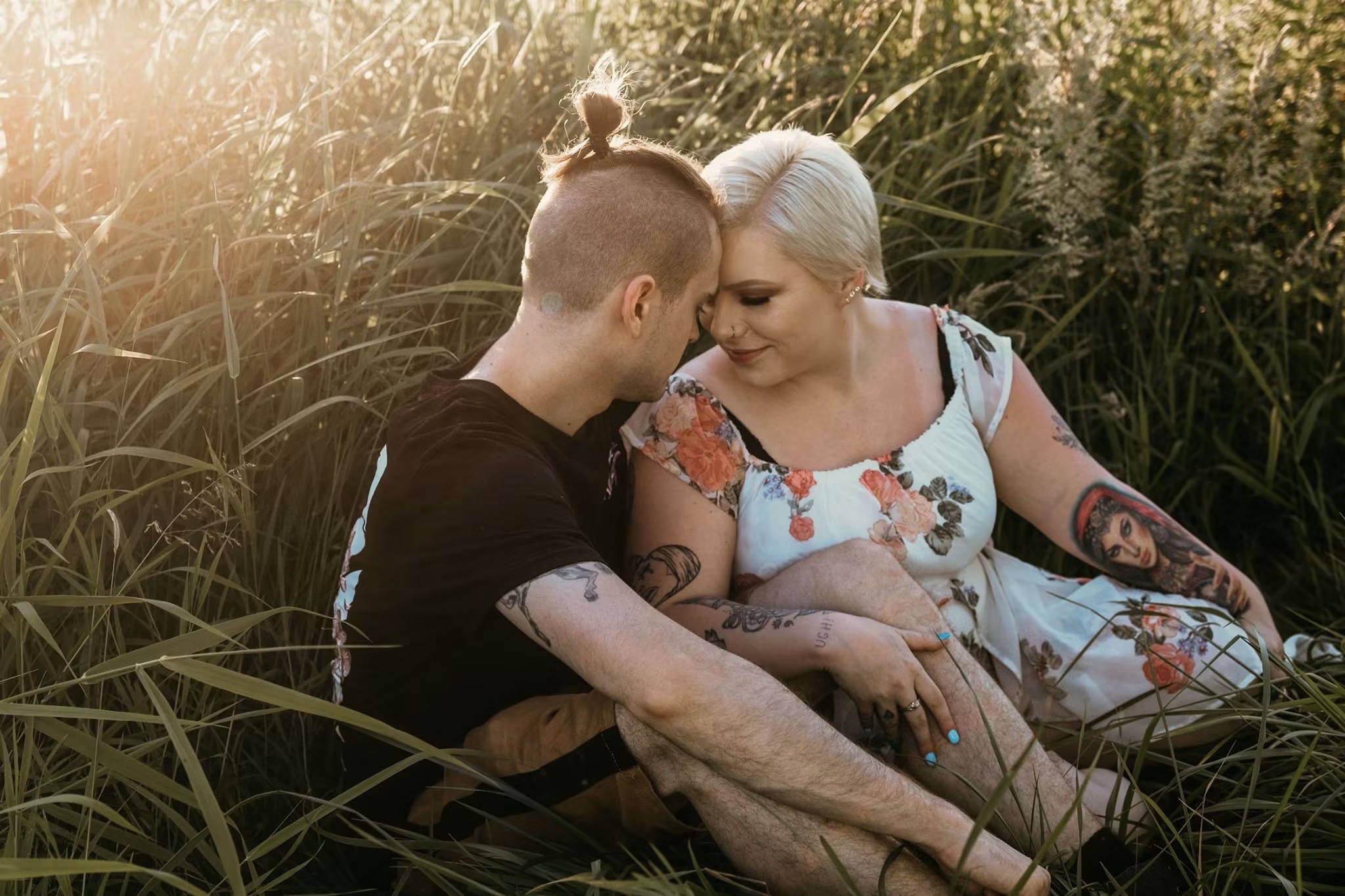 Couple leaning together in golden tall grass at sunset — McManus Photography