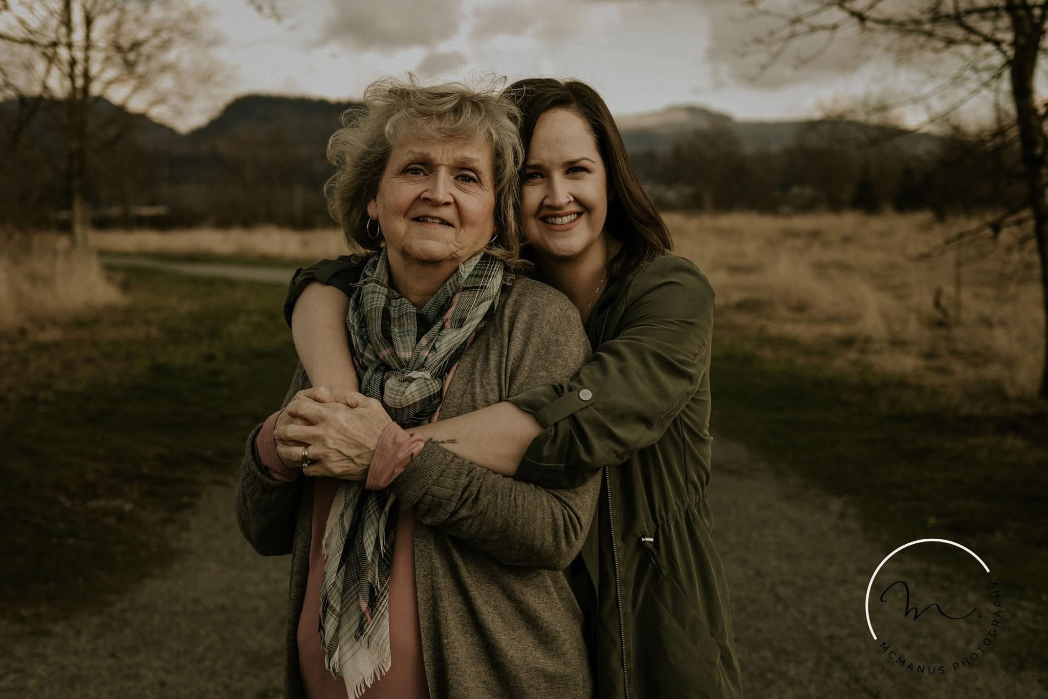 A daughter hugging her mother from behind on a valley trail