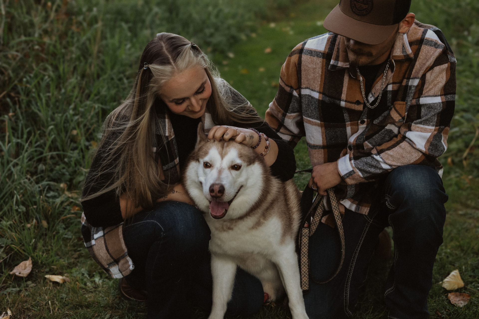Couple with their husky in the grass