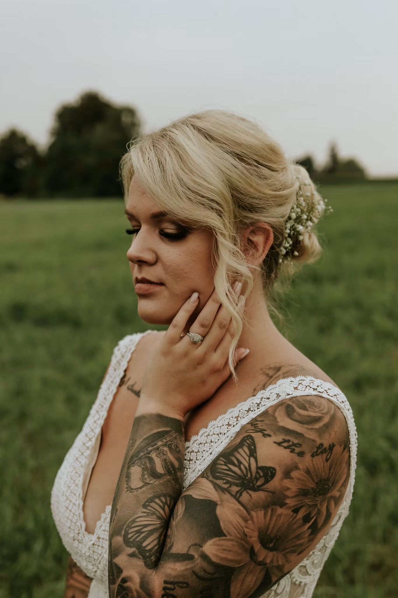 A bride in a lace gown pausing in an open field at dusk