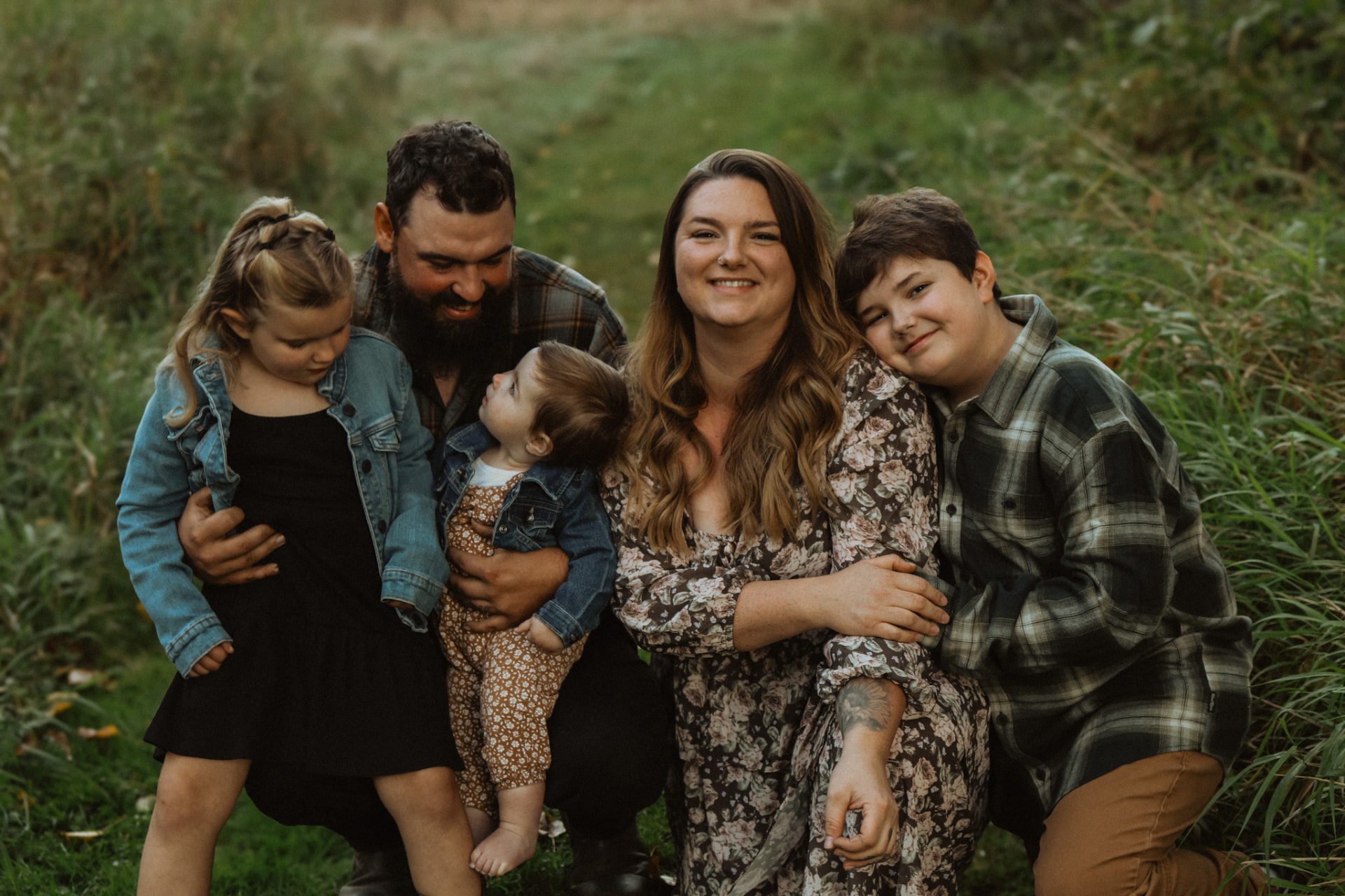 Family of five crouched together smiling in a field