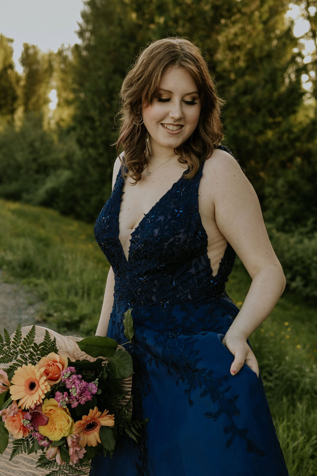 Portrait of a young woman in a navy gown holding a bright bouquet