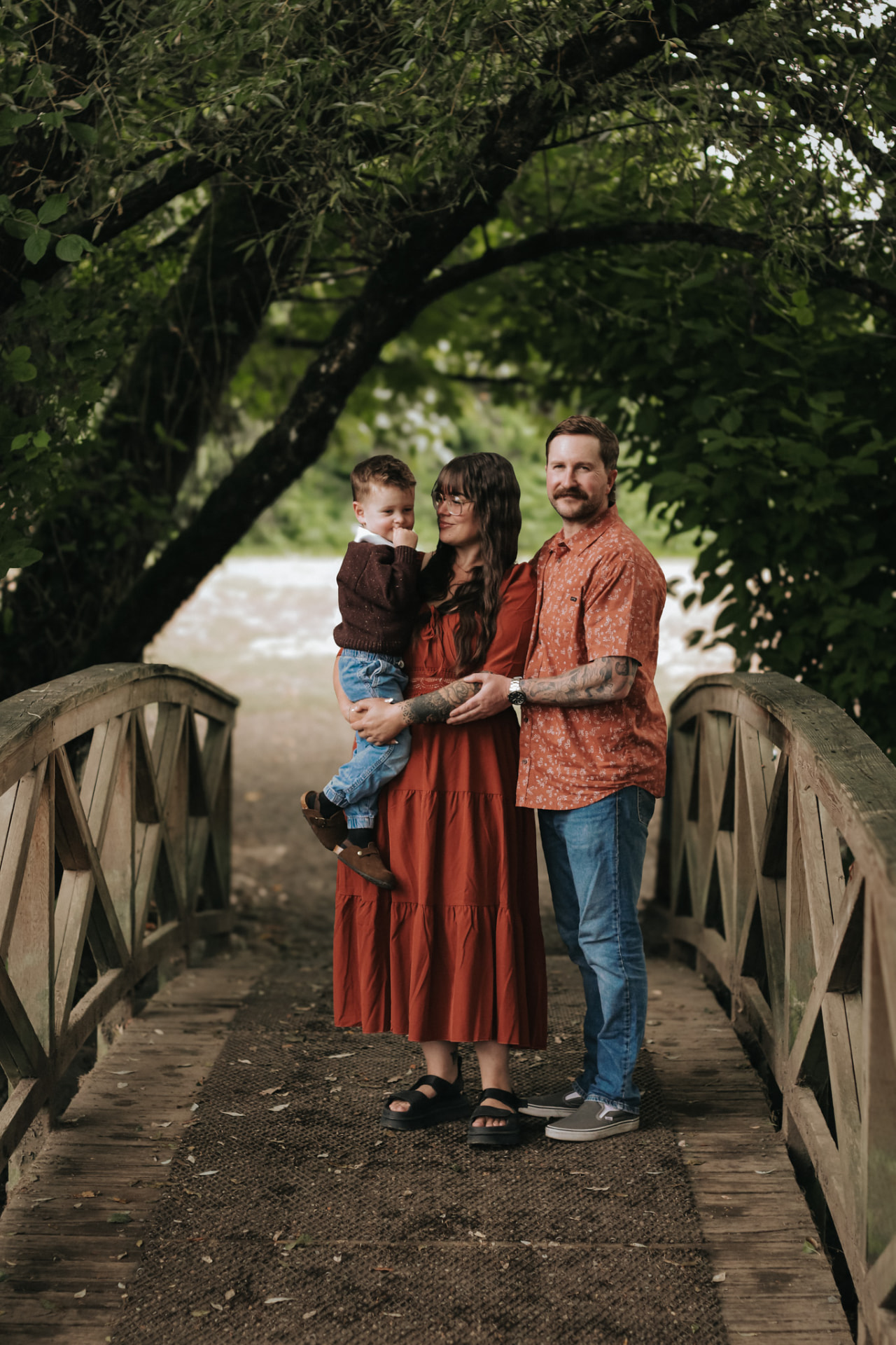 Family of three on a wooden bridge by the river