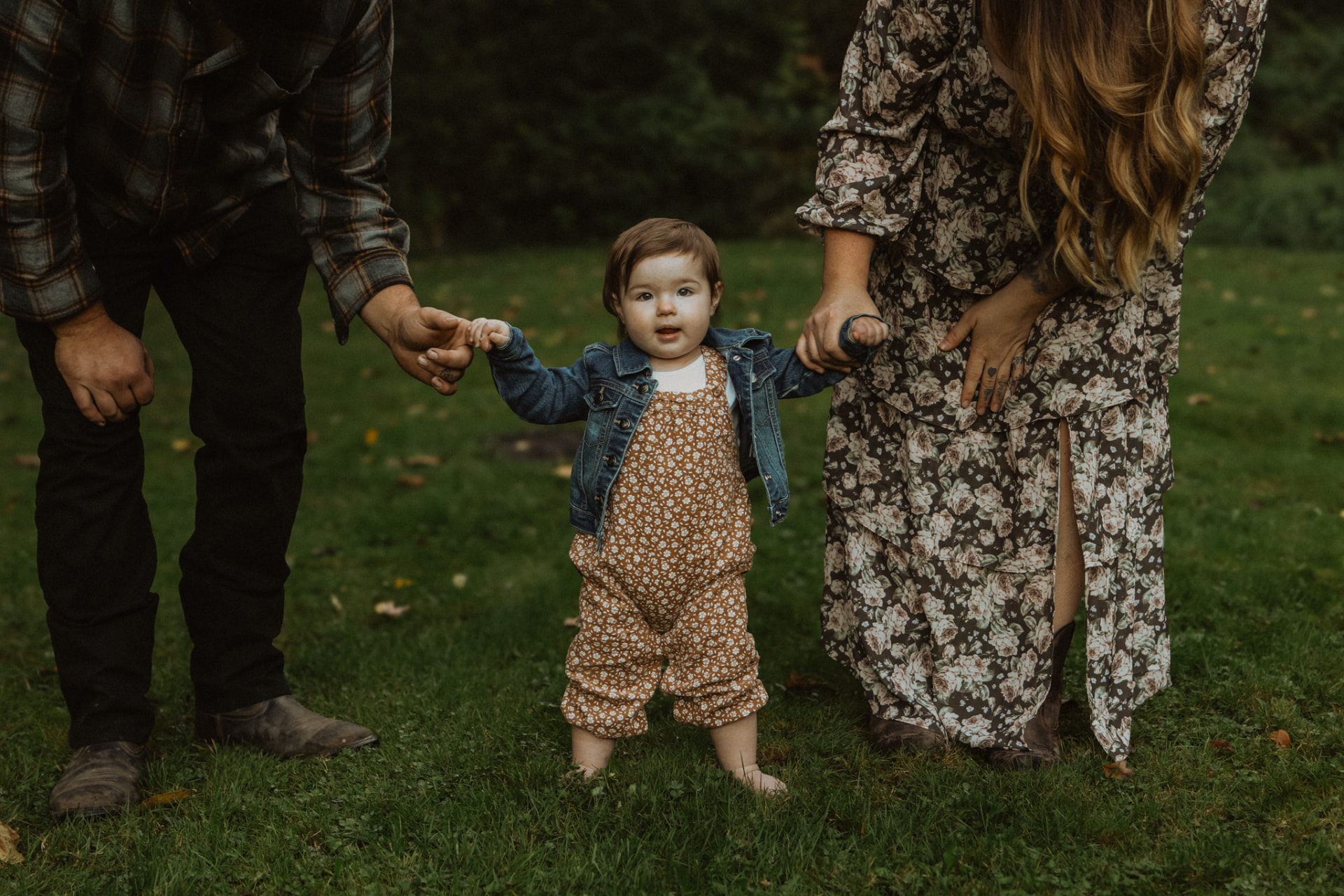 Toddler walking between her parents holding their hands