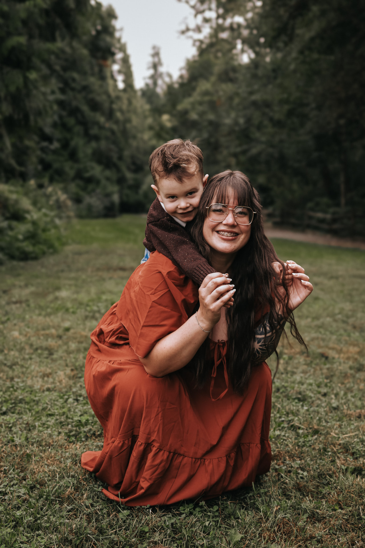 Mother giving her son a piggyback in a forest clearing