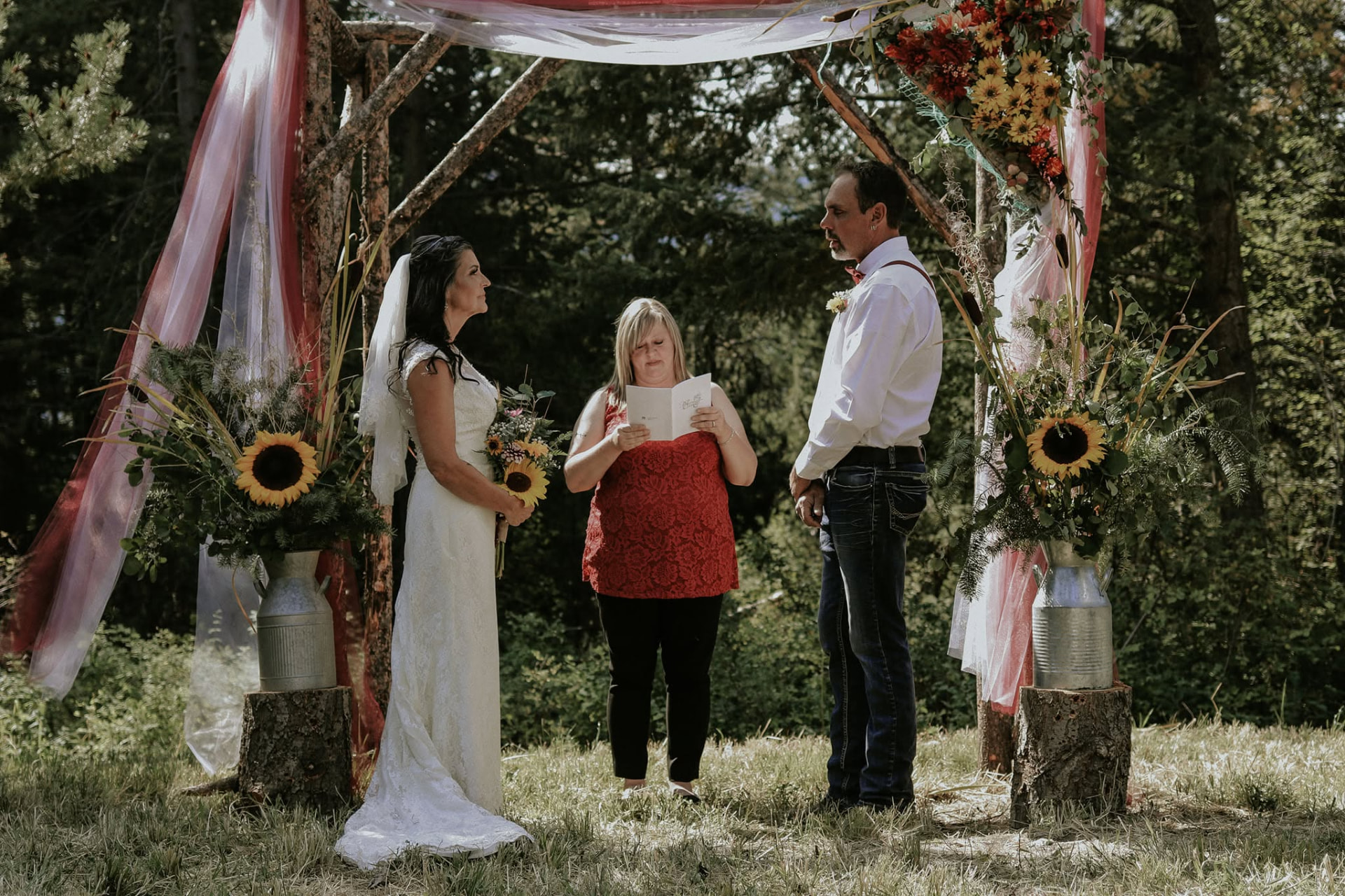 Outdoor ceremony under a floral arch in the trees