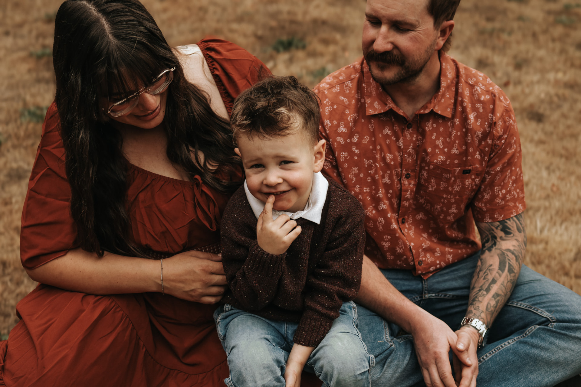 Parents laughing with their young son in a golden field