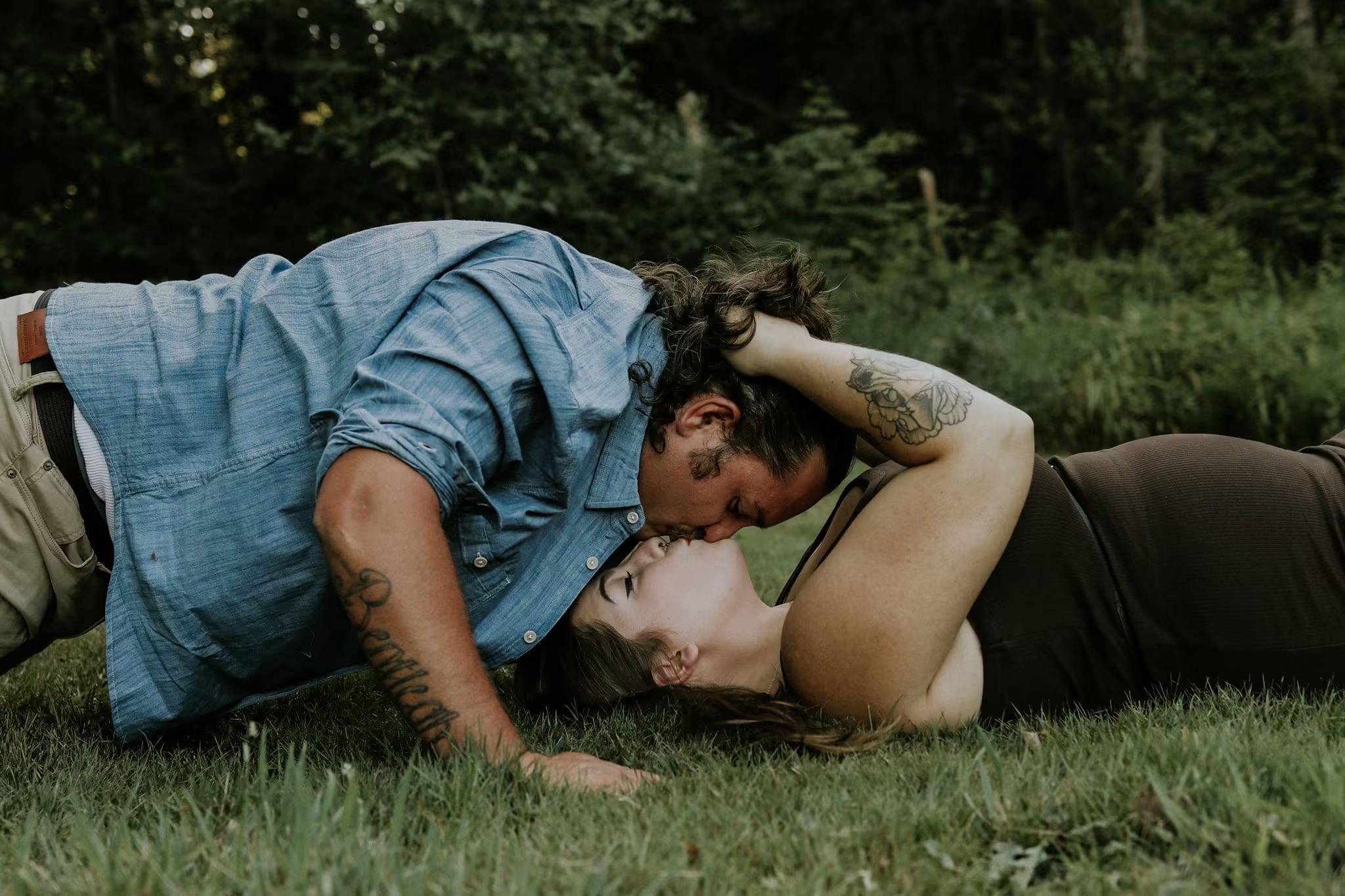 Couple lying in the grass sharing a quiet kiss — McManus Photography